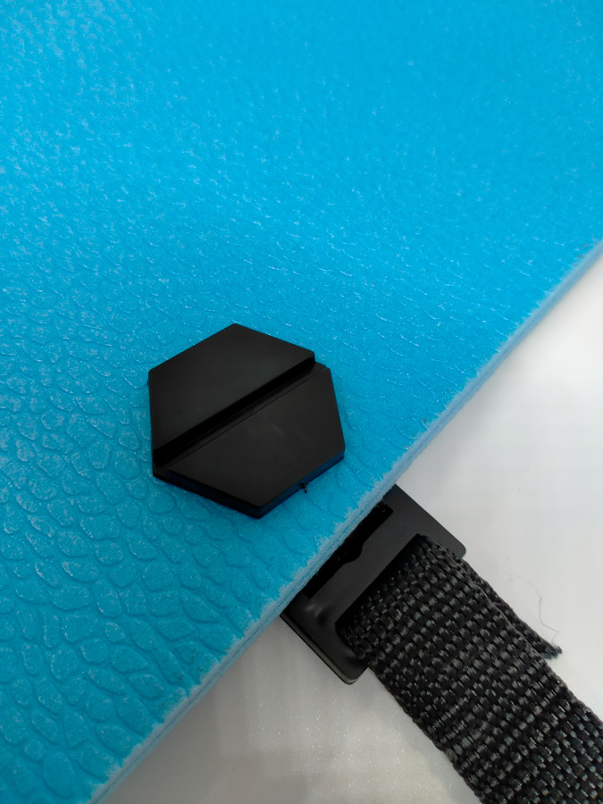 Pool Express - A black hexagonal clip is attached to a textured blue surface with a black strap threaded through a rectangular buckle.