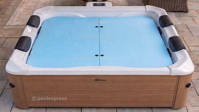 Pool Express - Square hot tub with a wooden exterior, four black headrests, and a blue cover split down the middle, placed on a tiled patio.